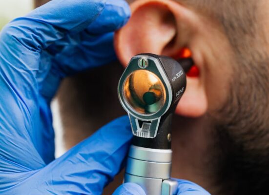 Close-up of a doctor using an otoscope to examine a patient's ear.