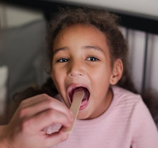 A young girl having her throat examined during a home medical checkup.