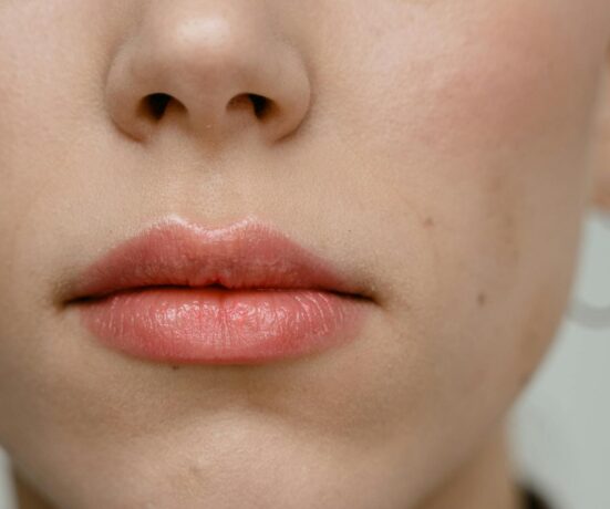 A detailed close-up of a woman's lips showcasing pink lipstick and subtle makeup.