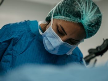 a surgeon wearing a surgical mask and scrubs his face